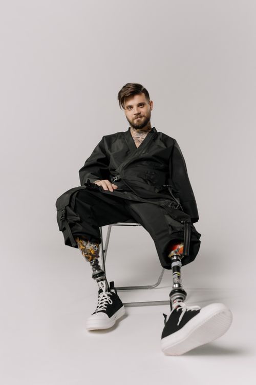Free Stylish man with prosthetic legs sits confidently in a studio setting. Stock Photo