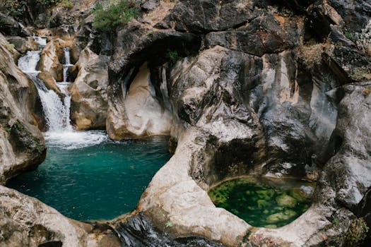 Picturesque scenery of waterfall flowing among rocks and falling in water stream in canyon