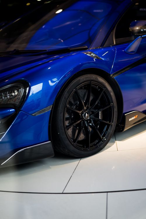 Free Close-up of a blue supercar's wheel and body, highlighting its sleek design in a London showroom. Stock Photo