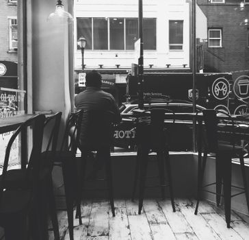 Monochrome image of a man in a Philadelphia café, view of street outside.