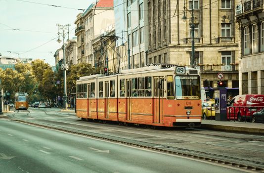Charming vintage tram on a bustling European street lined with historic buildings.