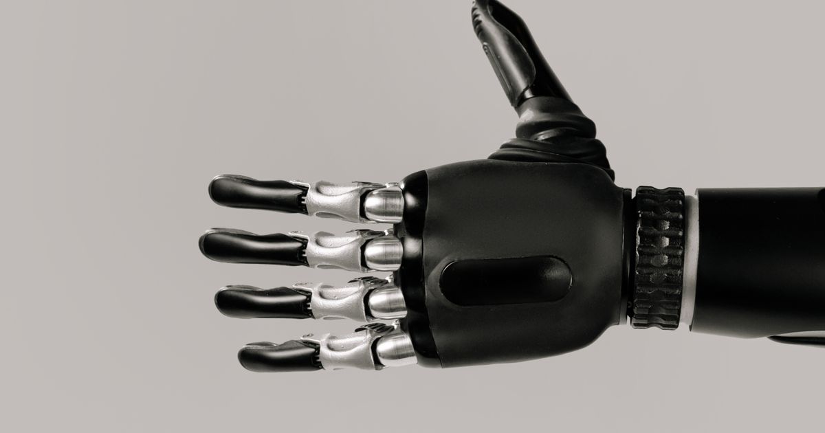 A detailed view of a sleek black and silver robotic prosthetic hand against a neutral background