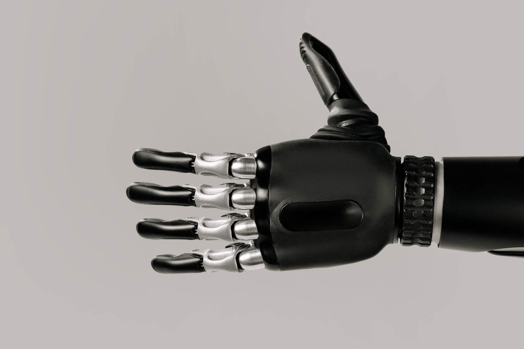 Primer plano de una mano robótica metálica con dedos articulados sobre fondo oscuro