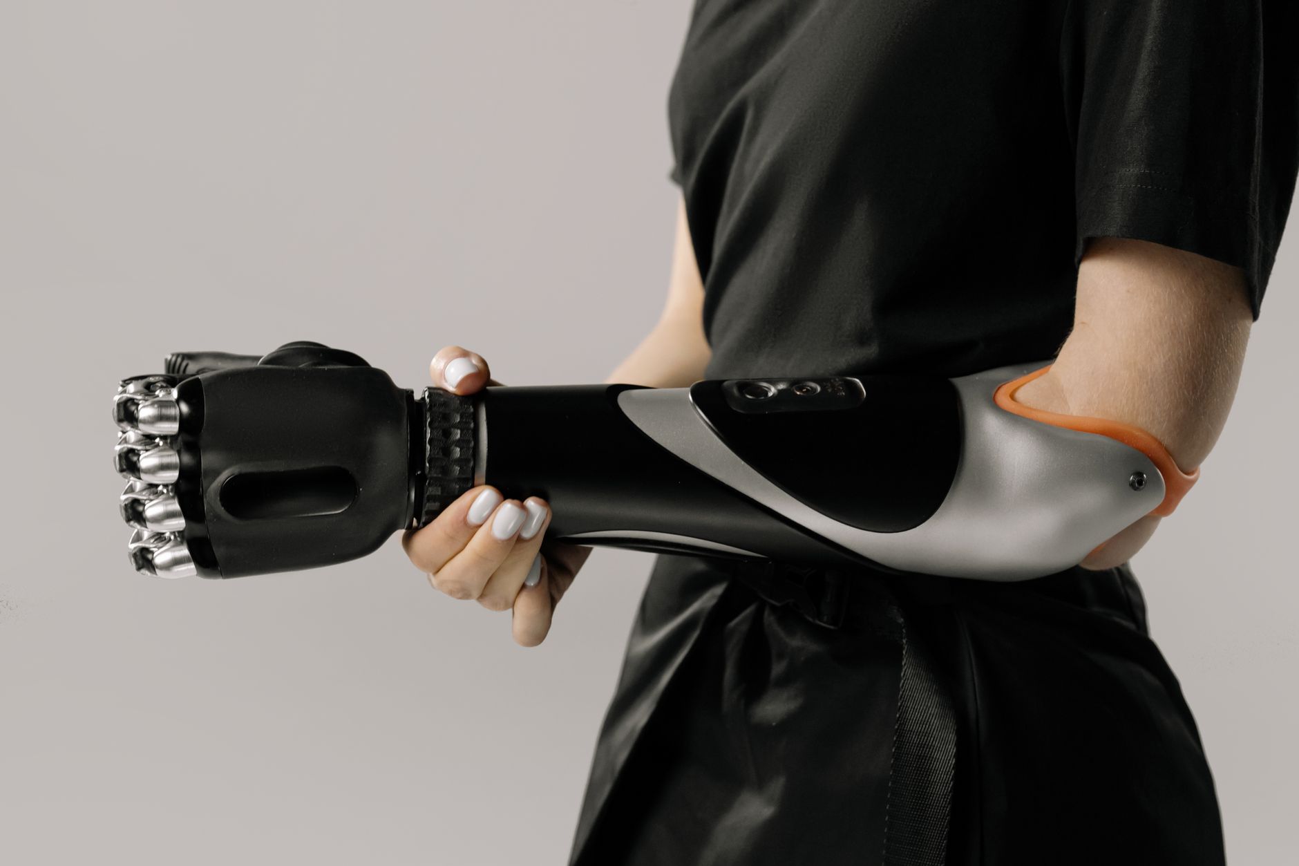 Close-up of a woman holding a sleek black prosthetic arm in a studio setting.