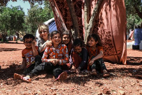 Free Group of happy children playing and smiling outdoors in a refugee camp in Idlib, Syria. Stock Photo