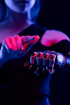 Close-up of a woman using a high-tech prosthetic arm in dramatic lighting, showcasing modern technology.