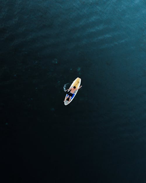 Free Man lying on paddleboard in sea Stock Photo