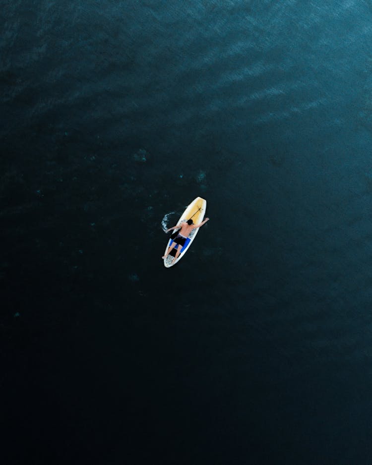 Man Lying On Paddleboard In Sea