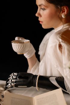 Woman with prosthetic arm elegantly holding a tea cup at a table.