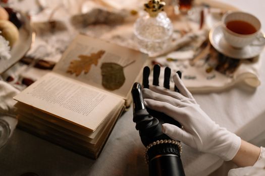 Close-up of a prosthetic hand with a white glove on a decorated table setting.
