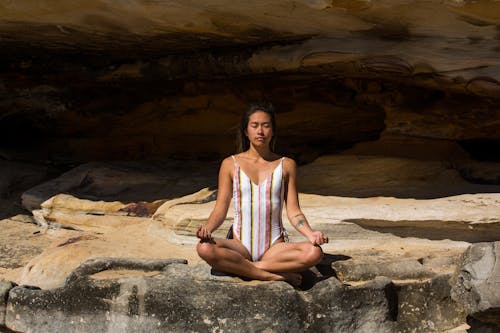 Woman in Swimsuit Meditating on Rocks