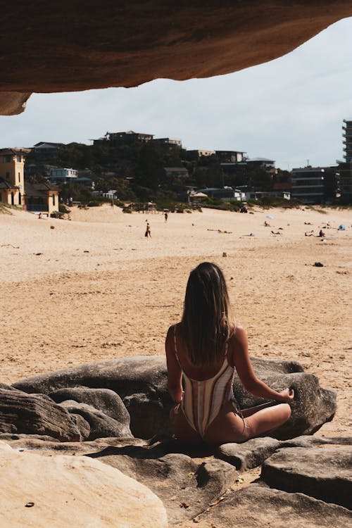 Back View of a Woman Meditating on a Rock