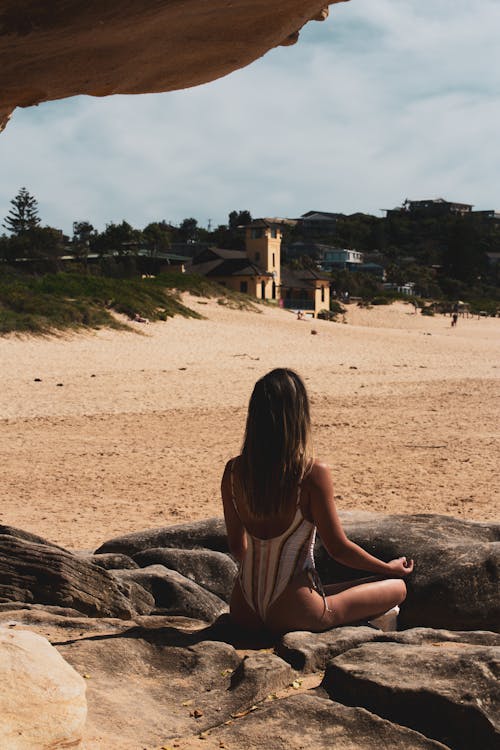 Back View of a Woman Meditating on Rock