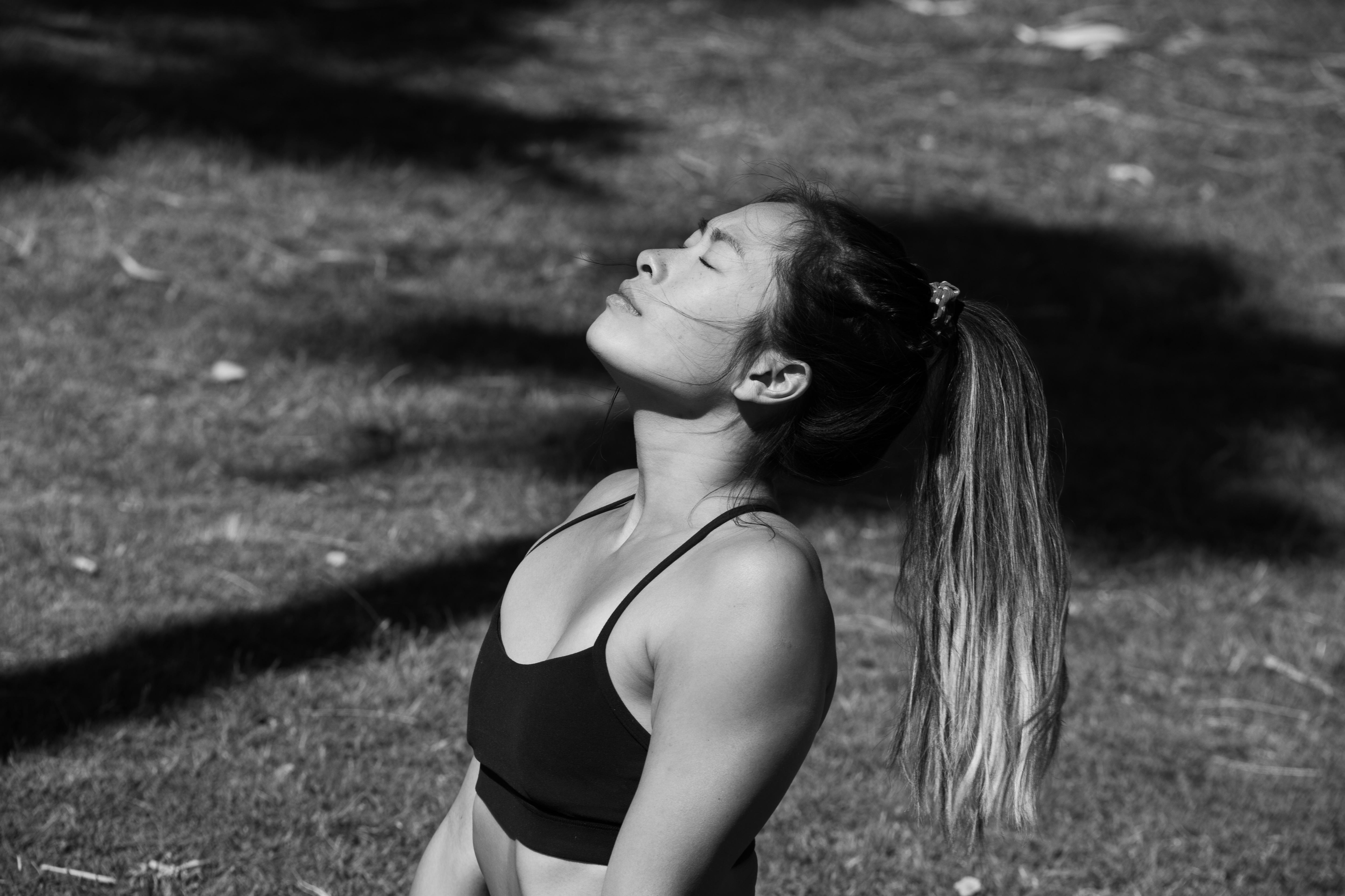 Foto en blanco y negro de una mujer meditando al aire libre con los ojos cerrados.