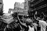 Black and white of anonymous multiracial activists with placards fighting for human rights in city