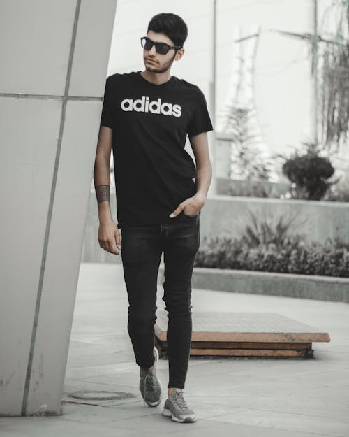 Man in Black Adidas T Shirt Leaning on a Post