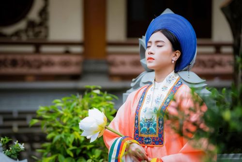 Free Woman in traditional Vietnamese attire holding a white lotus flower outdoors. Stock Photo