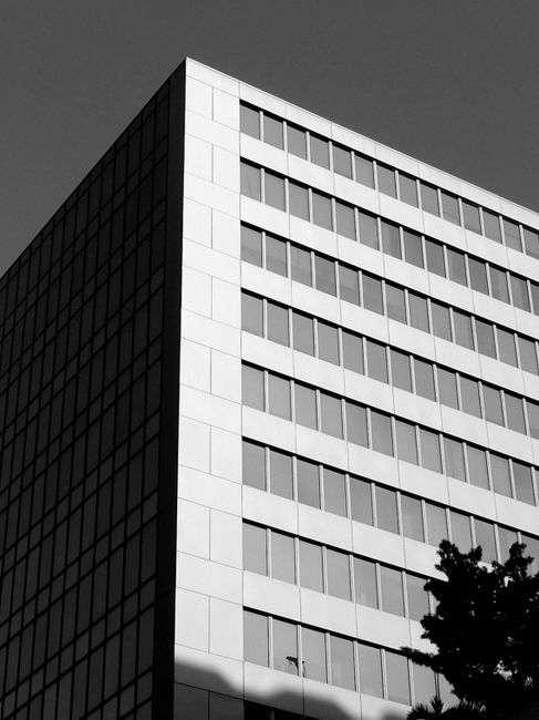 From below black and white of modern geometric exterior of building under sky in city street