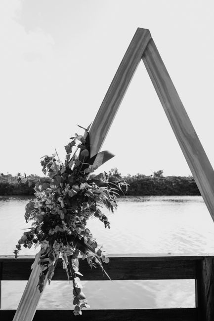 Black and white of blooming flower bouquet on triangular wedding arch for festive occasion on veranda over pond