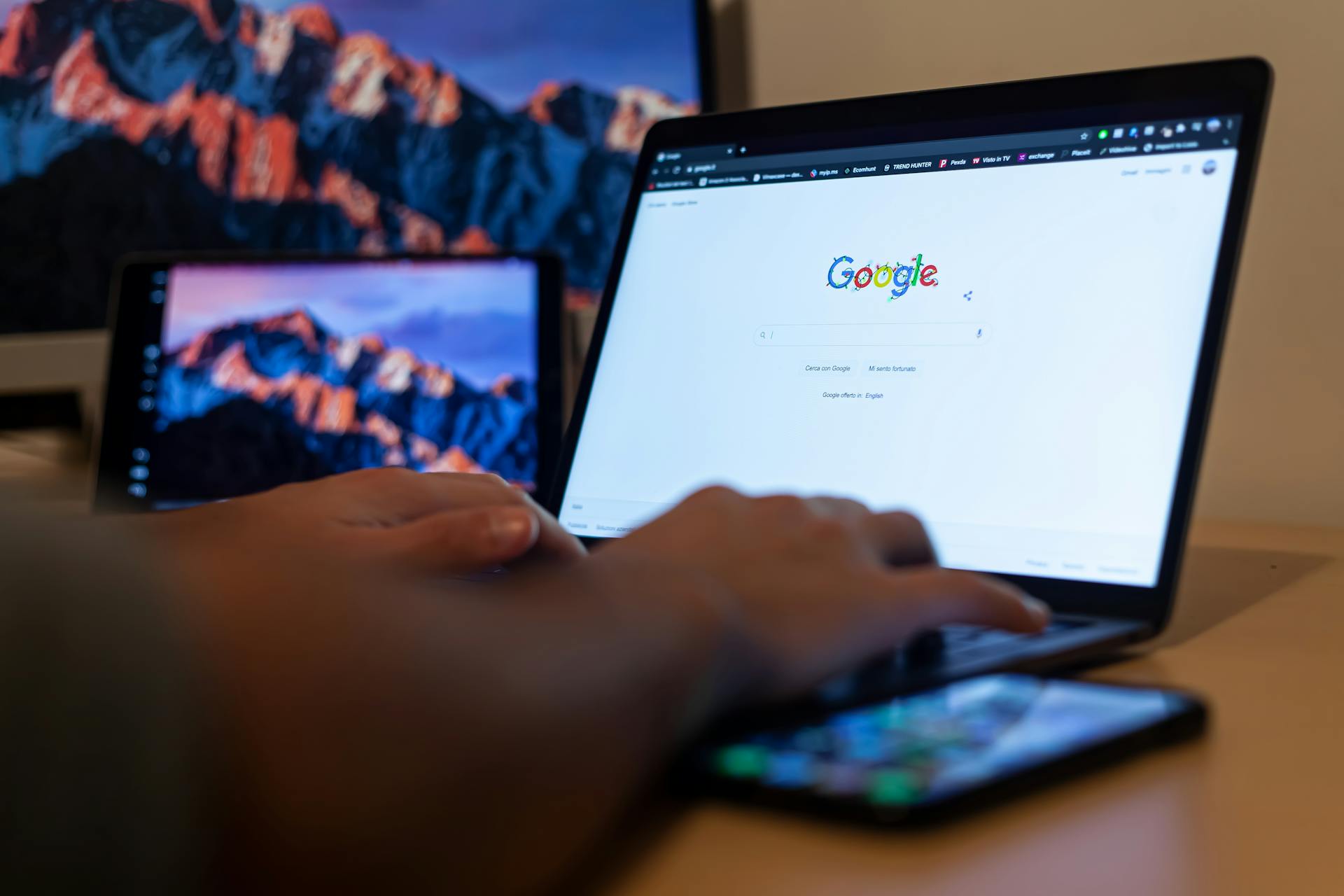 Hands typing on a laptop with Google on screen, in a remote work setup in Milan, Italy.