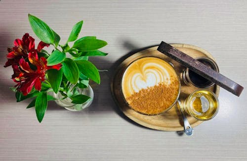 Free Close-Up Shot of Cup of Coffee beside a Flower Vase Stock Photo