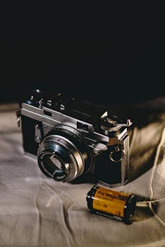 Vintage camera and roll on fabric, highlighting retro photography charm.