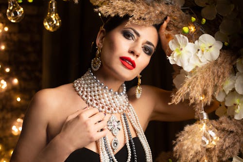 Woman with pearl necklace  standing in room with decorations and looking at camera