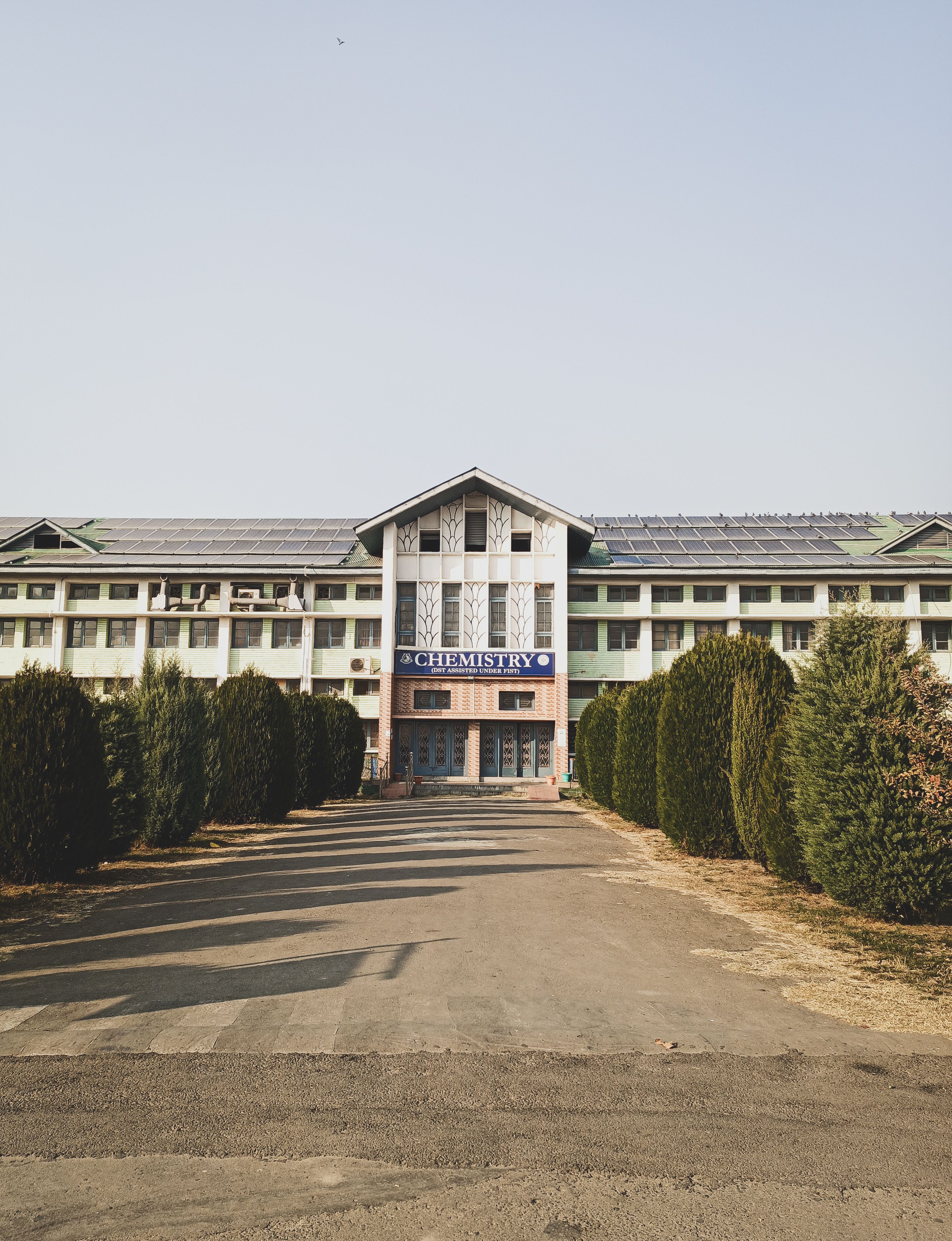 Front view of a modern building with a Chemistry department sign surrounded by greenery.