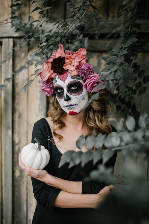 A Woman in a Halloween Costume Holding a Pumpkin