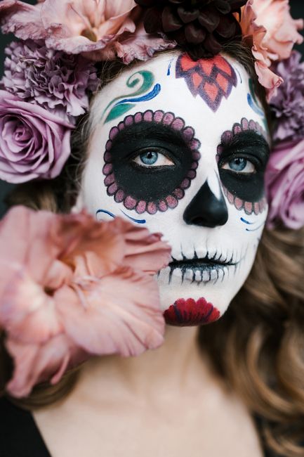 Captivating portrait of a woman with intricate Dia de los Muertos makeup and a vibrant flower crown.