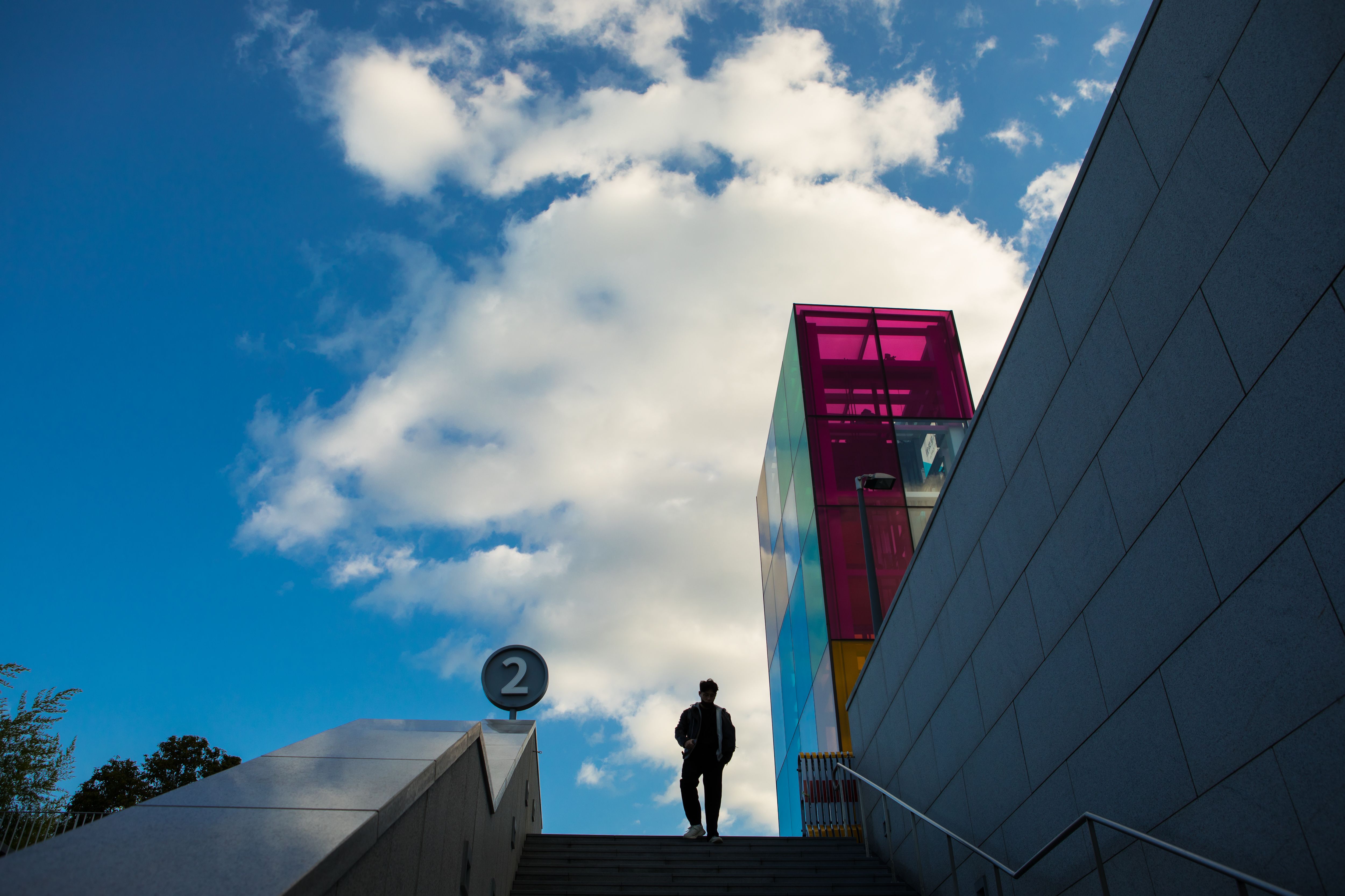 Silhouette of a person descending vibrant colored steps against a clear sky.