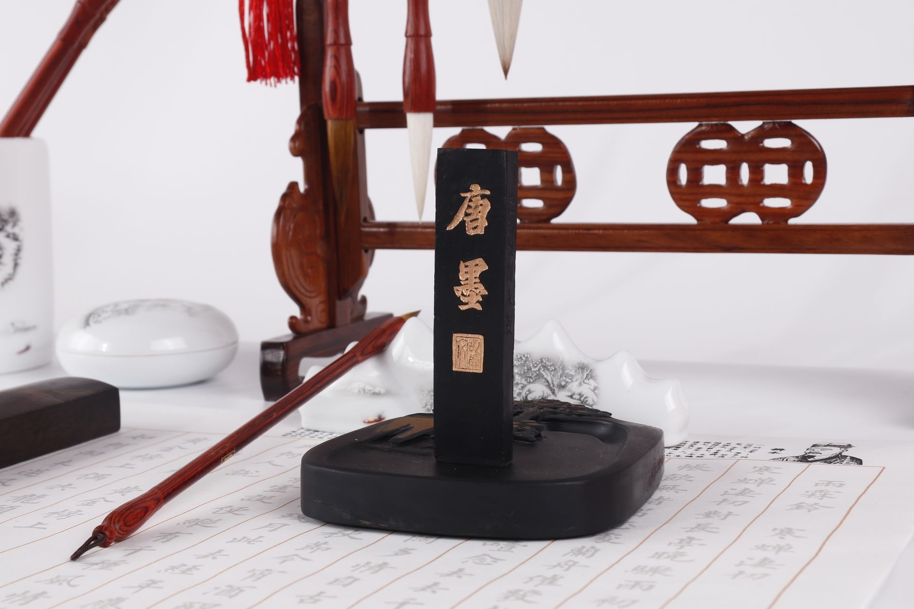 Elegant display of Chinese calligraphy tools including brushes, ink stick, and holder on a scroll.
