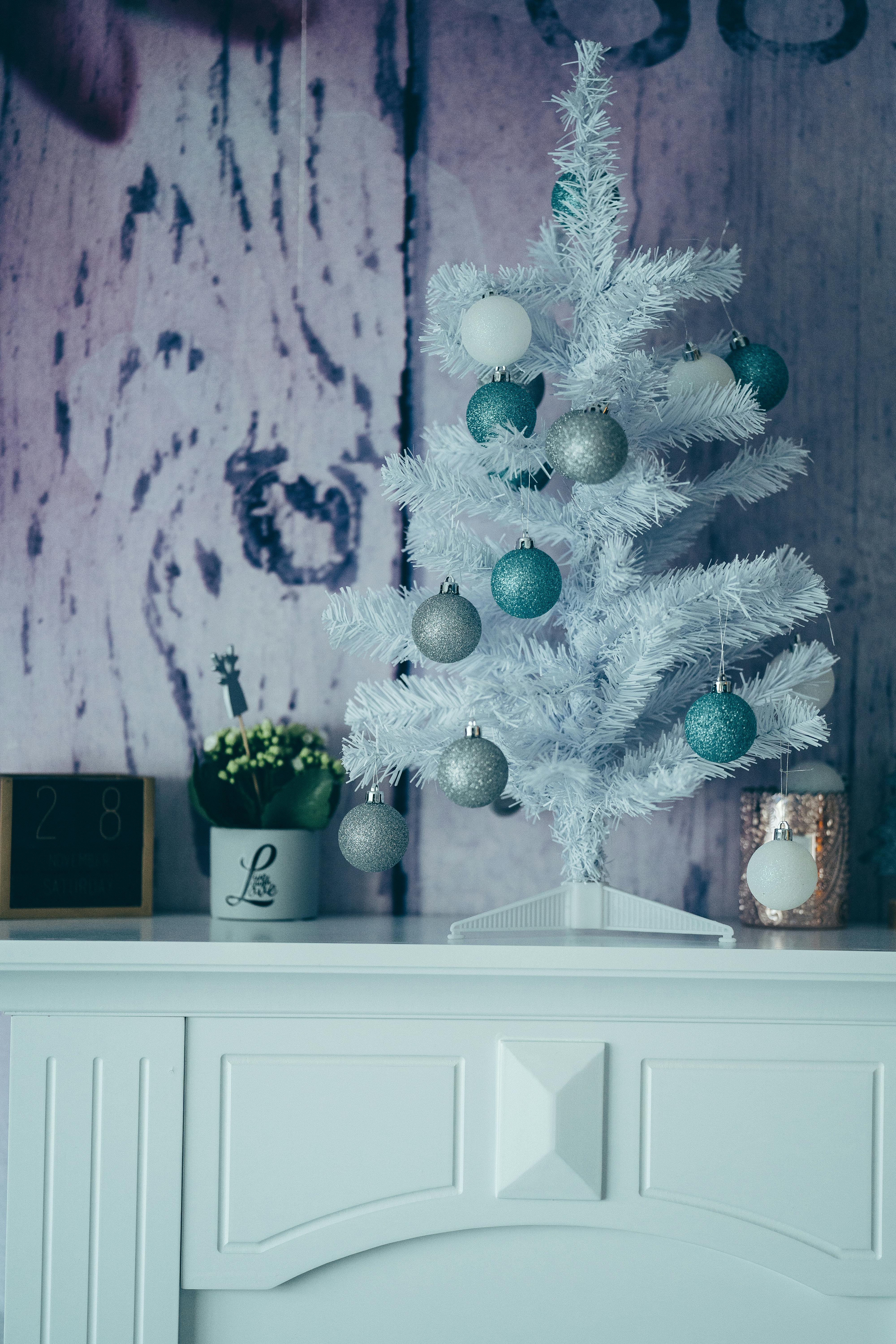 Free Stylish white Christmas tree decorated with teal and silver ornaments on a mantel. Stock Photo