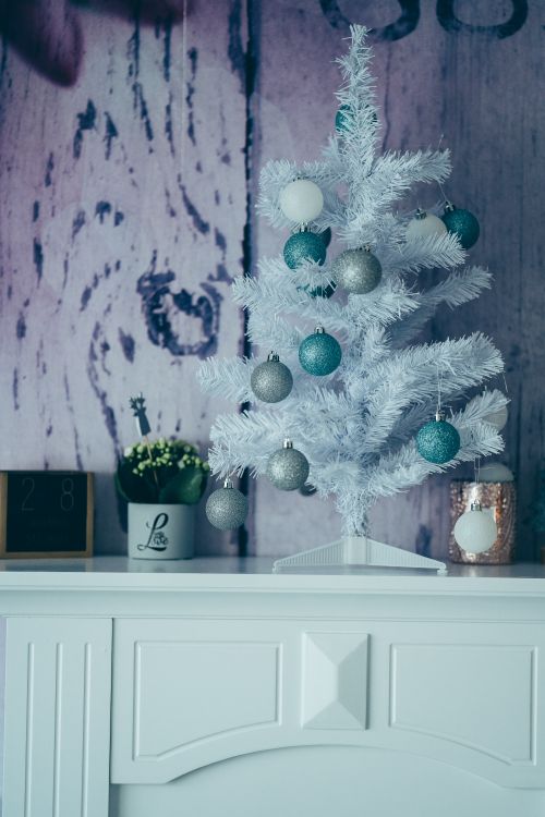 Free Stylish white Christmas tree decorated with teal and silver ornaments on a mantel. Stock Photo