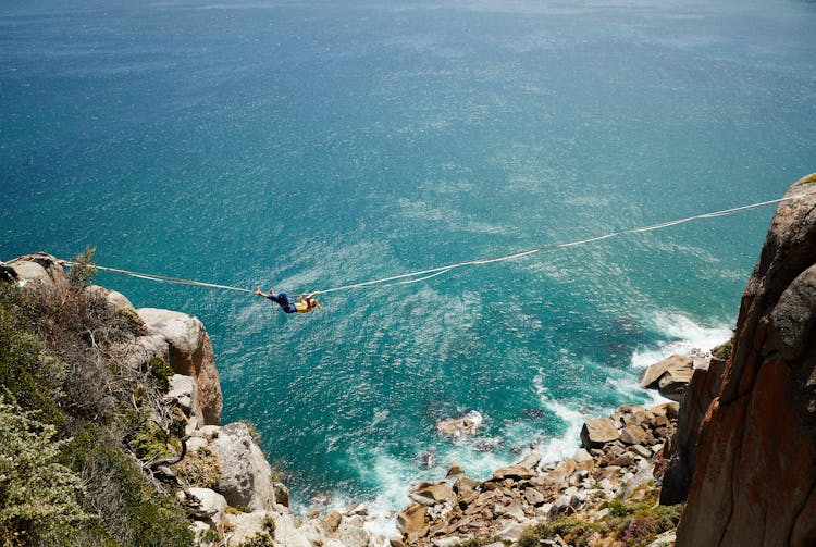 Anonymous Woman On Zipline Over Stony Coast