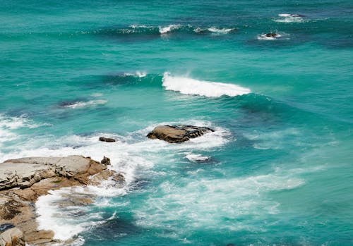 Wavy turquoise sea water near stones