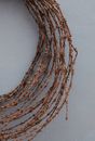Top view of wreath wickered of thin vines placed on white surface in studio