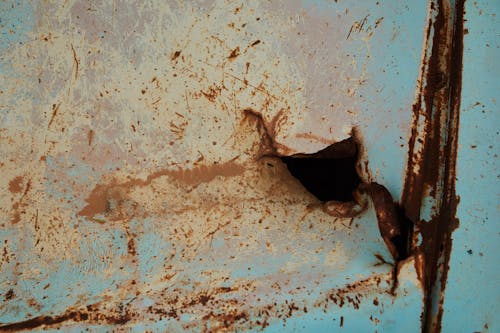 Old rusty metal surface of blue color with scratches and hole in abandoned building