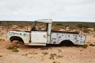 Rusty abandoned car near fence in desert