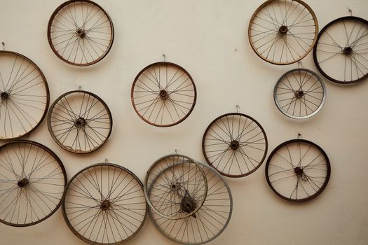 Different shapes and sizes spoke wheels hanging on light wall