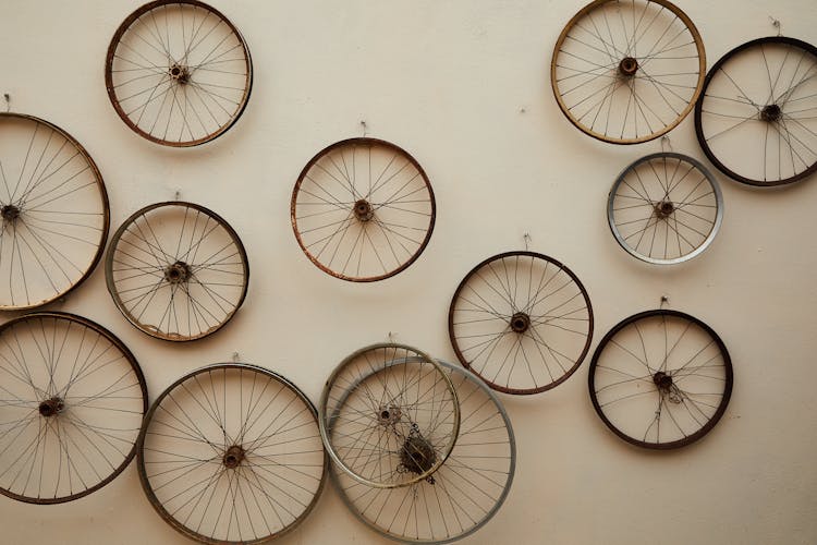 Different Shapes And Sizes Spoke Wheels Hanging On Light Wall