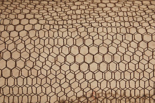 From above of rough textured lattice of iron material constructed on beige surface