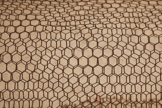 From above of rough textured lattice of iron material constructed on beige surface