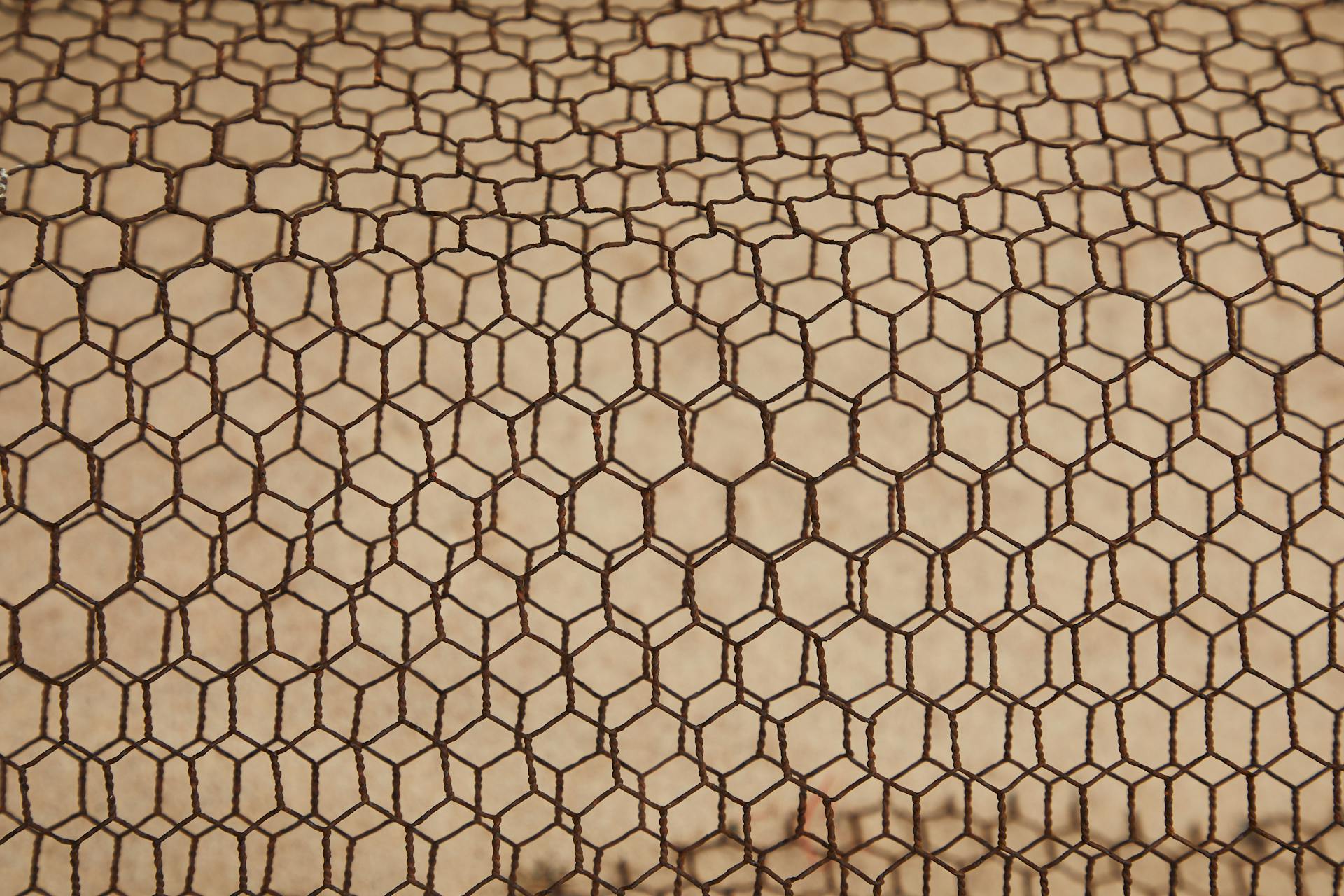 From above of rough textured lattice of iron material constructed on beige surface