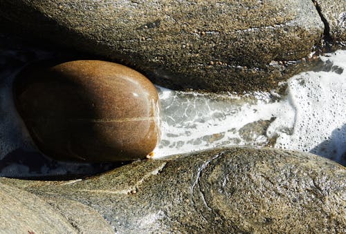 Rough stones on foamy water of river