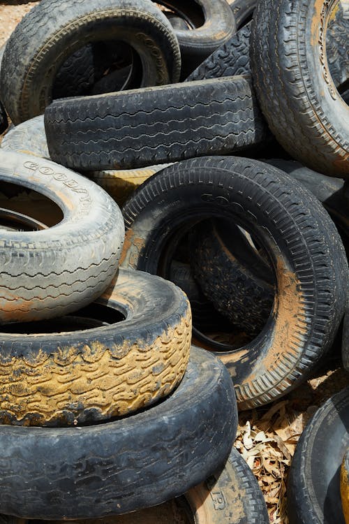 Free Heap of textured many dirty tires placed on ground with sawdust in daytime Stock Photo