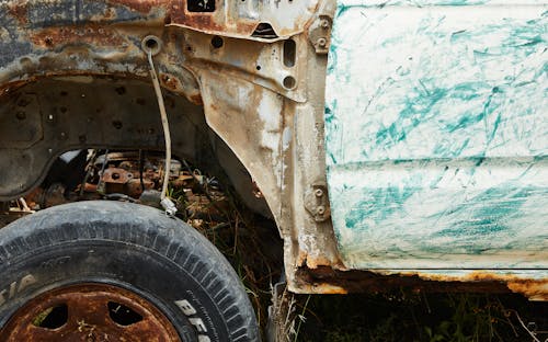 Aged metal rusty damaged car on grass