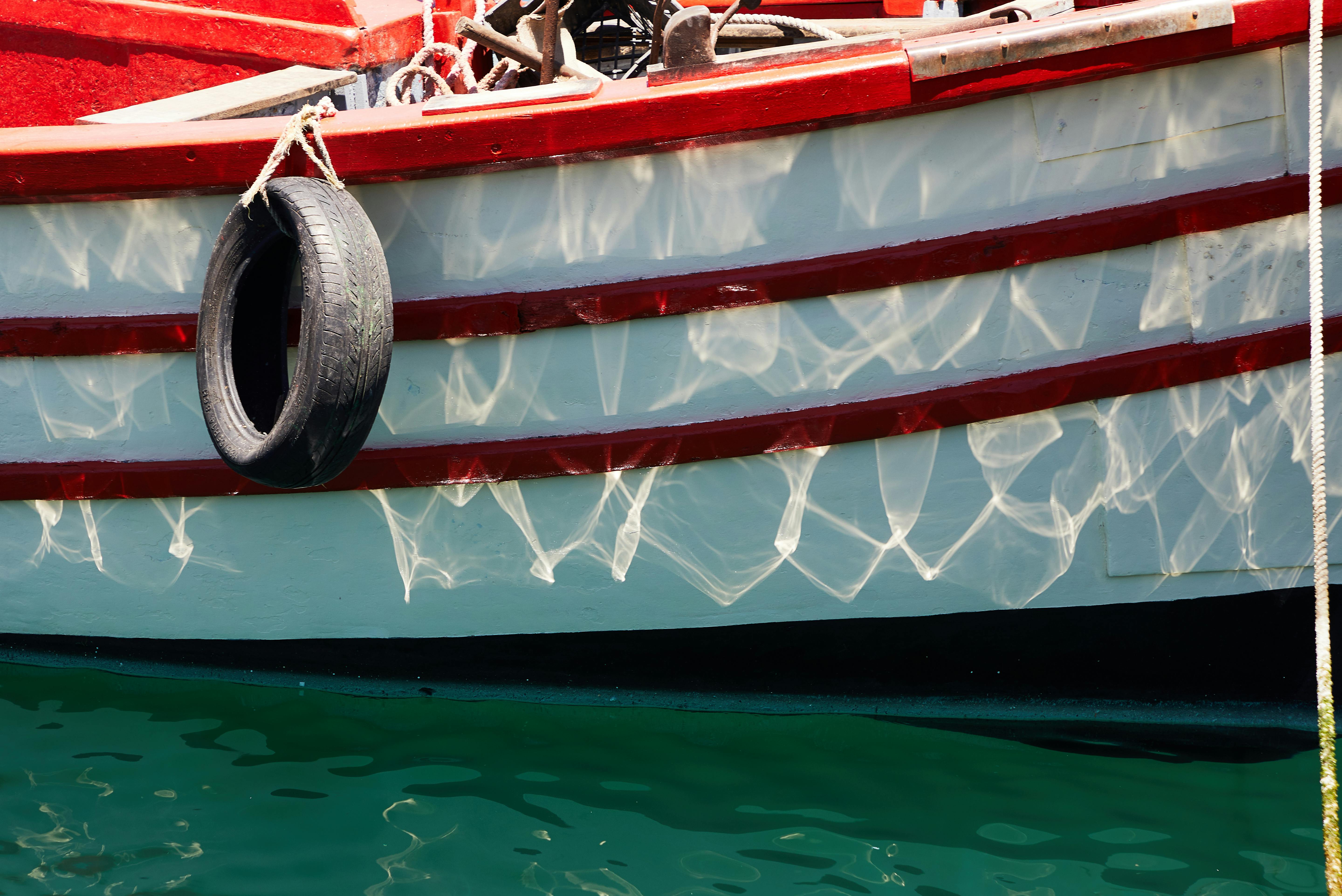 boat with reflection of water and tire hanging on rope