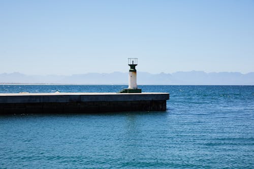 Old lighthouse on pier among rippling water of sea