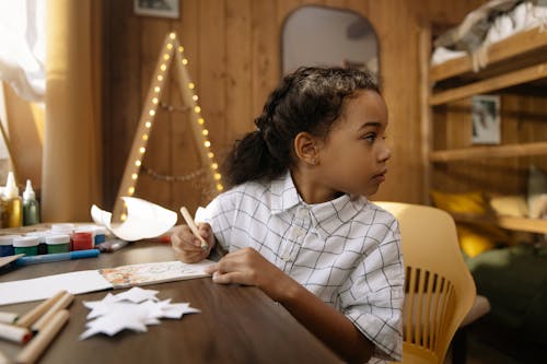 Free A Girl Making a Christmas Letter While Looking Away Stock Photo